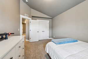 Bedroom with visible vents, baseboards, light colored carpet, and vaulted ceiling