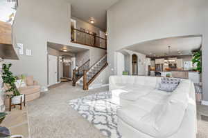 Living area with visible vents, a notable chandelier, stairway, arched walkways, and a high ceiling