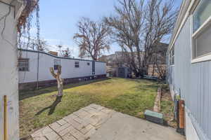 View of yard with a storage unit, a patio, an outbuilding, and fence