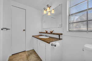 Half bath with toilet, vanity, and tile patterned flooring