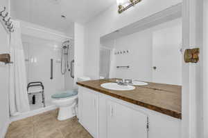 Full bathroom with toilet, a stall shower, vanity, and tile patterned flooring