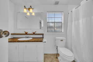 Full bathroom featuring visible vents, baseboards, toilet, and vanity