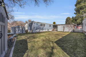 View of yard with a storage shed, an outdoor structure, and fence