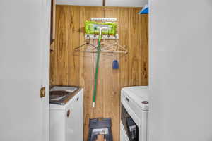 Clothes washing area with wooden walls, washing machine and dryer, and laundry area