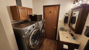 Clothes washing area featuring washer and dryer, dark wood-style floors, cabinet space, and a sink