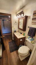 Half bathroom with vanity, toilet, and wood finished floors