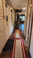 Hallway with brick wall, a textured ceiling, a baseboard heating unit, and wood finished floors