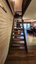 Staircase featuring wood finished floors, brick wall, and a textured ceiling