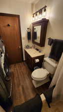 Bathroom featuring vanity, washer / clothes dryer, toilet, and wood finished floors