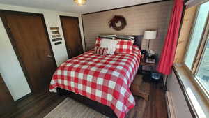 Bedroom featuring a baseboard heating unit, a textured ceiling, and wood finished floors