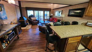 Kitchen featuring a breakfast bar, stainless steel dishwasher, a textured ceiling, open floor plan, and dark wood-style floors