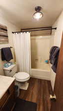 Bathroom featuring toilet, shower / bath combo, wood finished floors, and vanity