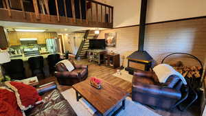 Living room featuring stairway, a wood stove, a high ceiling, and wood finished floors