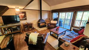 Living area with wood finished floors, a textured ceiling, a wood stove, and vaulted ceiling