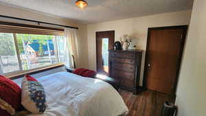 Bedroom with a textured ceiling and dark wood finished floors