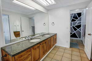 Full bathroom featuring tile patterned floors, a sink, a textured ceiling, and double vanity