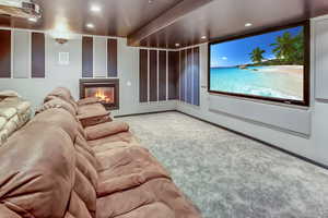 Carpeted cinema room featuring a glass covered fireplace and recessed lighting