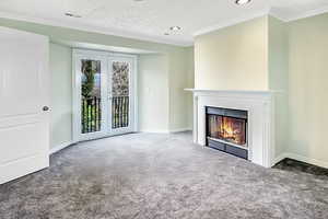 Unfurnished living room with visible vents, carpet flooring, french doors, and a glass covered fireplace