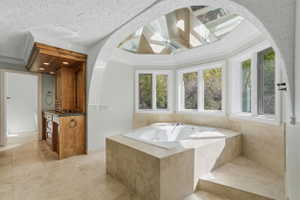 Primary bath featuring a skylight, ornamental molding, a garden tub, healthy amount of natural light