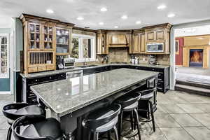 Kitchen featuring ornamental molding, a sink, custom range hood, appliances with stainless steel finishes, and a kitchen bar