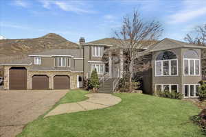 View of front of property featuring a front lawn, a chimney, driveway, and stucco siding