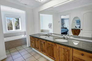 Bathroom with tile patterned floors, a textured ceiling, ensuite bath, and a sink