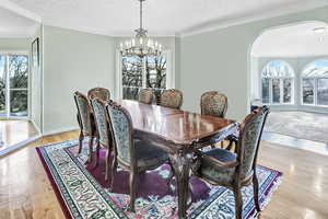 Dining space featuring a notable chandelier, a healthy amount of sunlight, light wood-style flooring, and ornamental molding