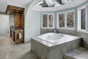 Full bathroom with vanity, a textured ceiling, a whirlpool tub, and crown molding