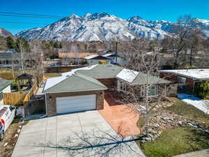 View of front of house featuring a mountain view, fence, brick siding, and a shingled roof