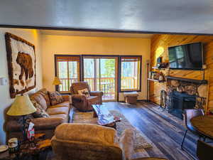 Living area with a fireplace, wooden walls, wood finished floors, and a textured ceiling