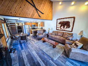 Living area featuring dark wood finished floors, a notable chandelier, recessed lighting, and a towering ceiling