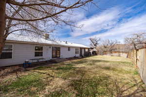 Back of property featuring a fenced backyard, a chimney, metal roof, and a lawn