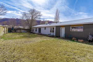 Back of house featuring metal roof, a yard, fence, and a mountain view