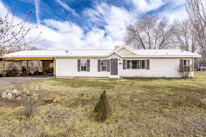 Ranch-style home with a carport, a front yard, and metal roof