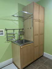 Clothes washing area featuring washer hookup, dark tile patterned floors, a sink, cabinet space, and baseboards