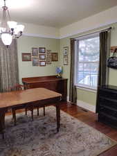 Dining space featuring a notable chandelier, wood finished floors, visible vents, and baseboards