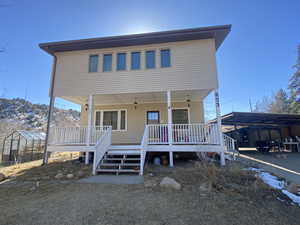 View of front of home featuring a greenhouse, a porch, and an outdoor structure