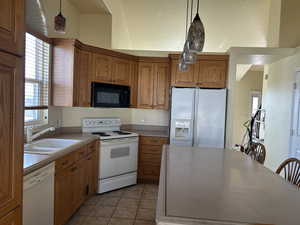 Kitchen featuring a sink, white appliances, pendant lighting, and light tile patterned floors