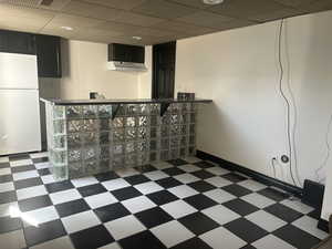 Finished basement with tile patterned floors, baseboards, and freestanding refrigerator