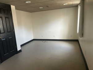 Empty room with a drop ceiling, baseboards, and concrete flooring