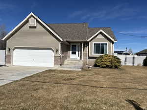 View of front of home with a shingled roof, fence, concrete driveway, a front yard, and a garage