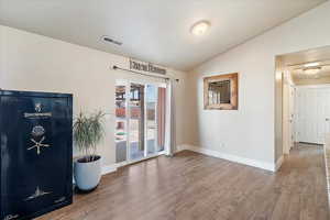 Empty room featuring baseboards, lofted ceiling, visible vents, and wood finished floors