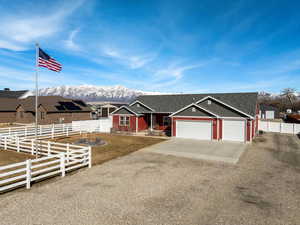 Ranch-style house featuring fence, a residential view, driveway, a garage, and a mountain view