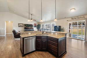 Kitchen with visible vents, a sink, open floor plan, dark brown cabinets, and dishwasher