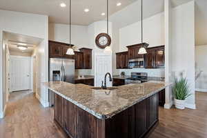 Kitchen with a sink, dark brown cabinetry, a high ceiling, and stainless steel appliances