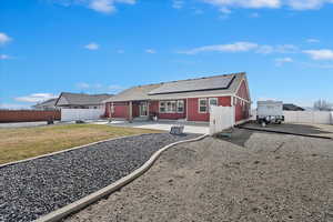 Back of house with a fenced backyard, roof mounted solar panels, a yard, and a patio