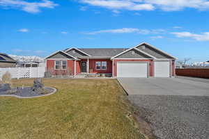 View of front of property featuring a front yard, fence, concrete driveway, a garage, and board and batten siding