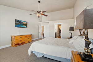 Carpeted bedroom with baseboards, ceiling fan, and a towering ceiling