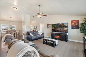 Living area featuring high vaulted ceiling, a ceiling fan, wood finished floors, and baseboards