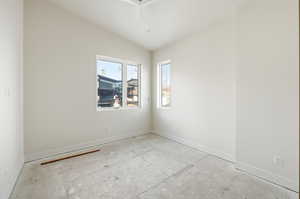Spare room featuring baseboards and vaulted ceiling